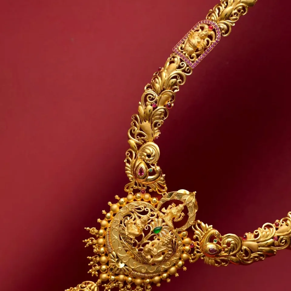 Long necklace with carved links and a round temple-motif pendant